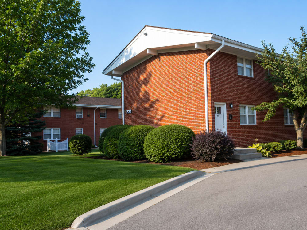 Brick apartment buildings surrounded by well-maintained lawns and lush greenery, sunny clear sky at South Oak in Ames, Iowa