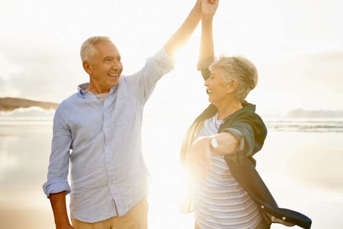 Resident couple from a MBK Senior Living community dancing on the beach