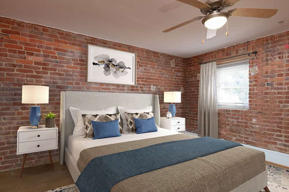 Apartment bedroom with ceiling fan and a large bed at High Street Lofts in Petersburg, Virginia