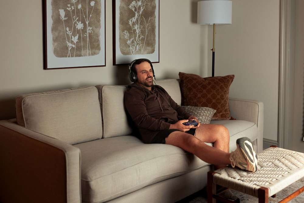 Resident playing games in a living room at The Waters at Promenade in Marrero, Louisiana