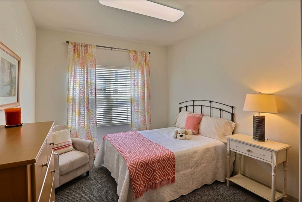 Resident bedroom with a side table and wall art at Milestone Senior Living Stoughton in Stoughton, Wisconsin.