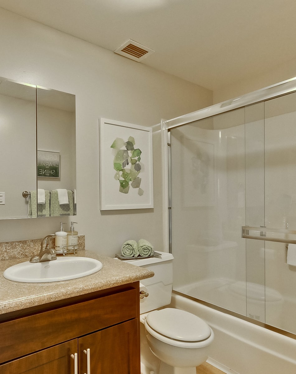 Modern bathroom with wood-style cabinetry in a model home at The Marc, Palo Alto in Palo Alto, California