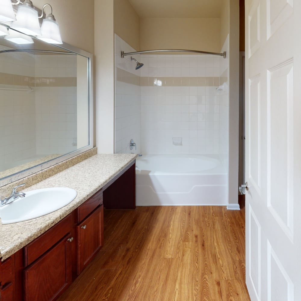 Large bathtub with hardwood floors at Oaks Estates of Coppell in Coppell, Texas