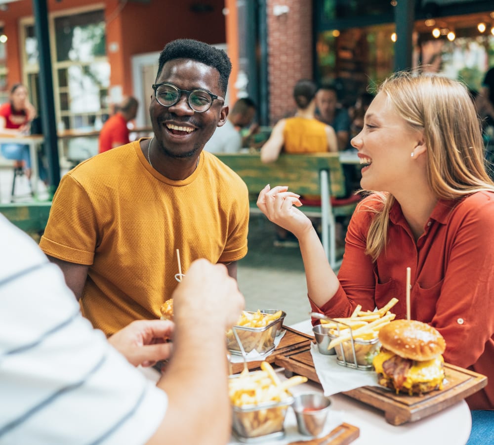 A smiling group of friends sharing a meal together outside a restaurant near Stonecreek Club in Germantown, Maryland