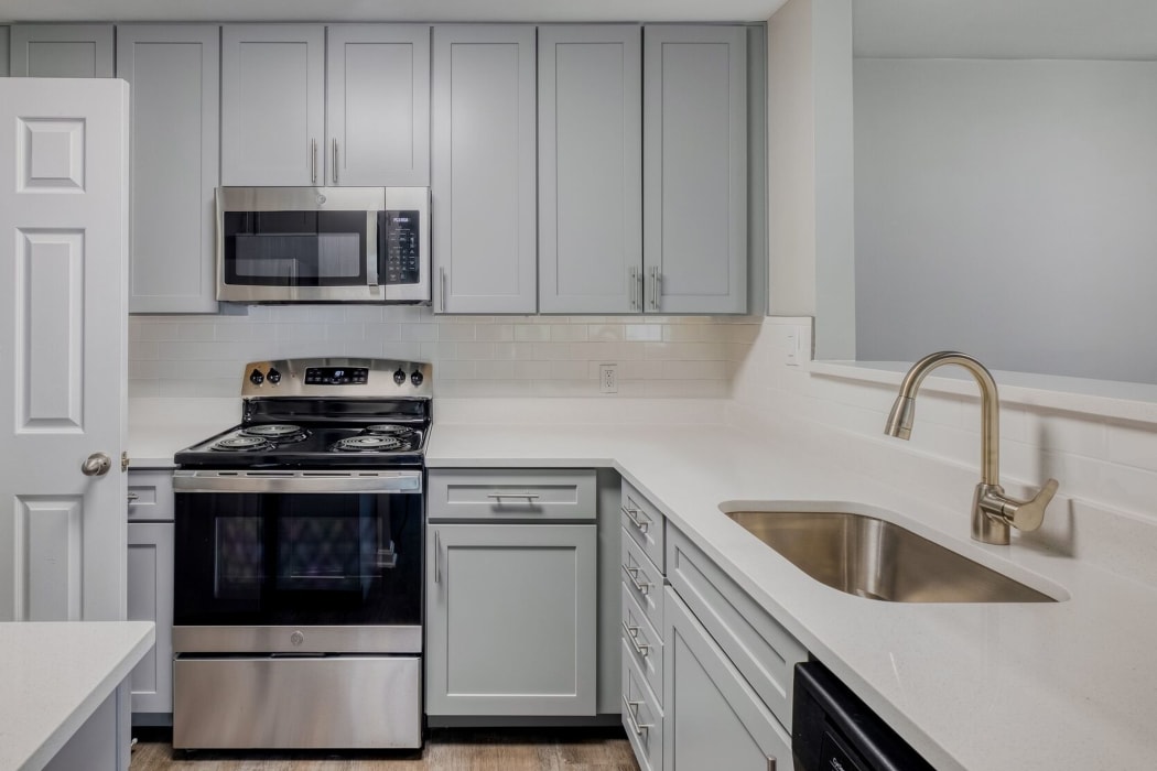 Open kitchen with stainless-steel appliances and gray cabinetry at Abbotts Run Apartments in Alexandria, Virginia. 