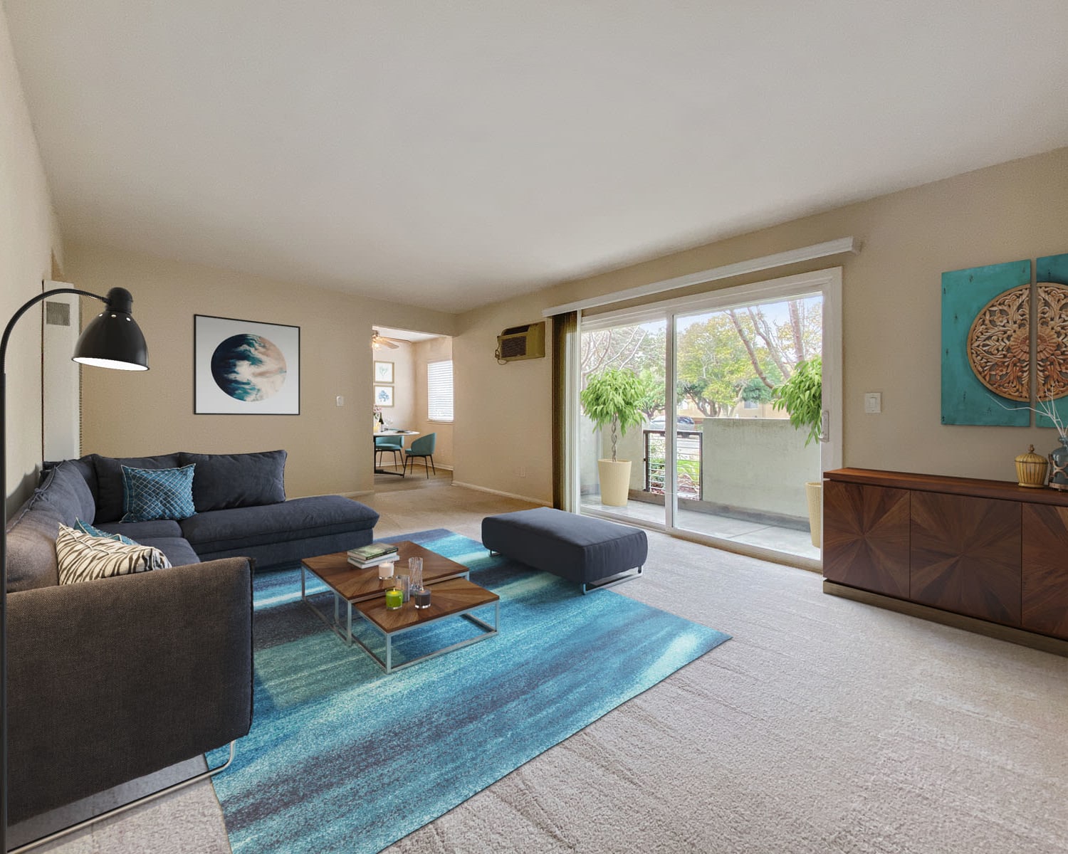 Sliding door leading to the private patio outside the well-furnished living area of a model home at Pleasanton Place Apartment Homes in Pleasanton, California