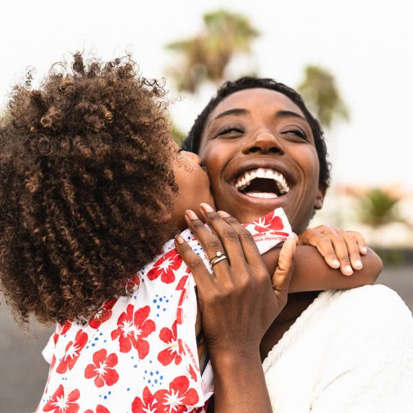 Mom smiles and hugs her child near Our Self Storage. 