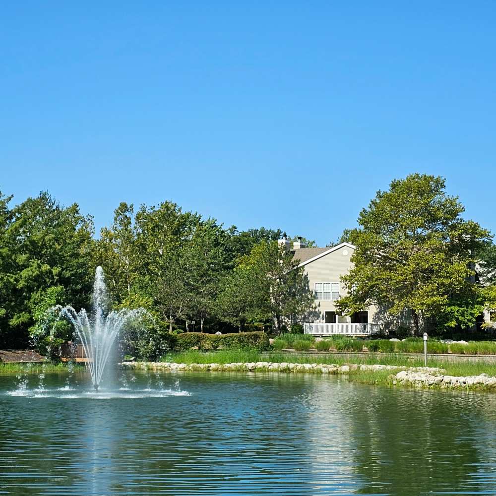 Serene waterfront view with a sparkling fountain and lush landscaping at Boulder Springs in Maryland Heights, Missouri.