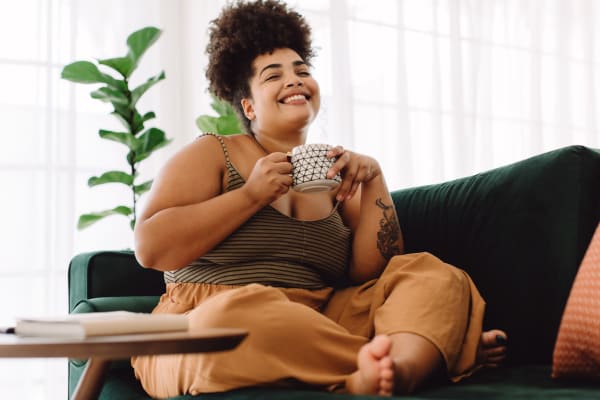 Resident smiling and drinking a cup of coffee in her living room at Stonegate Apartments in Elkton, Maryland