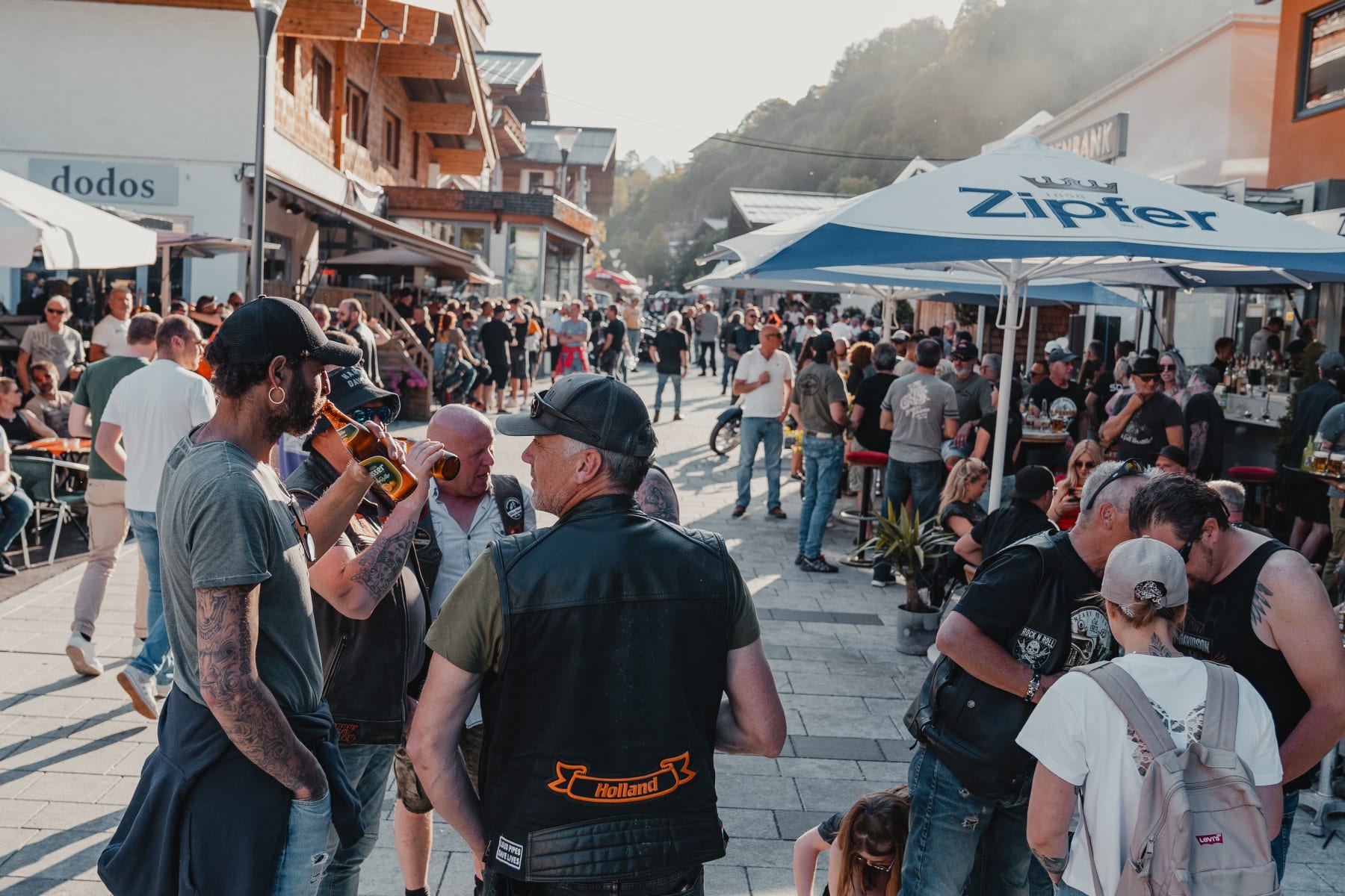 Viele Menschen feiern auf der Straße im Glemmtal. Es gibt Musik und Getränke.
