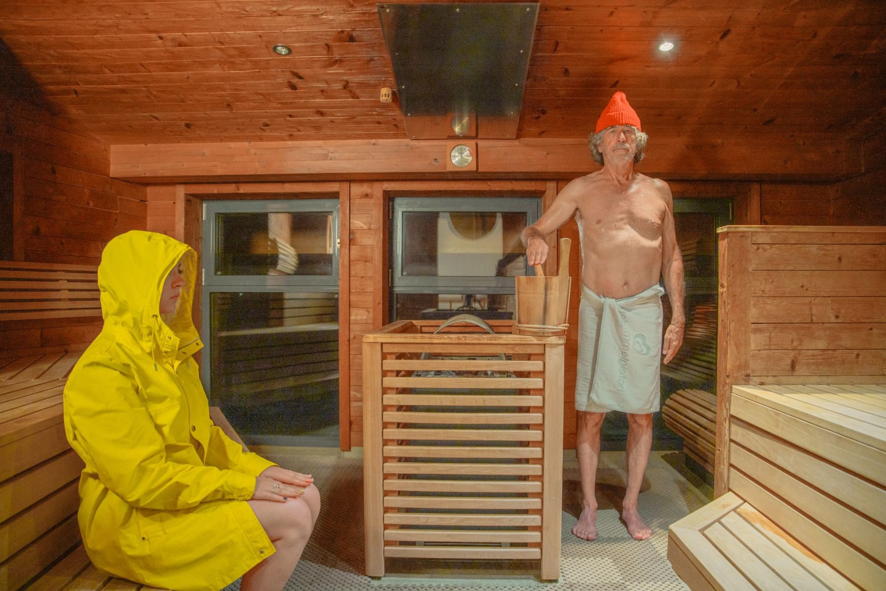 In einer Sauna im Glemmtal entspannen zwei Personen inmitten von Holzöfen und Dampfwolken.