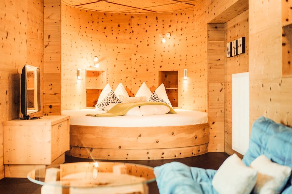 Gemütliches Zimmer im Glemmtalerhof mit Holzdesign und rundem Bett, ideal für Entspannung im Glemmtal.