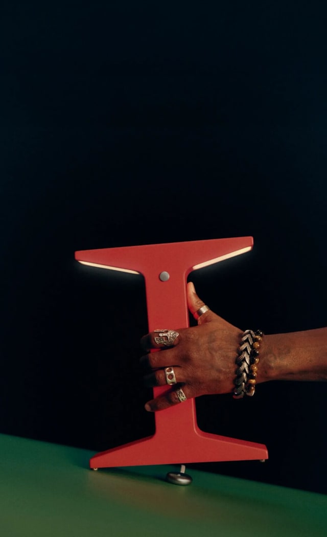 A hand holding a red Gantri Wireless light above a green table