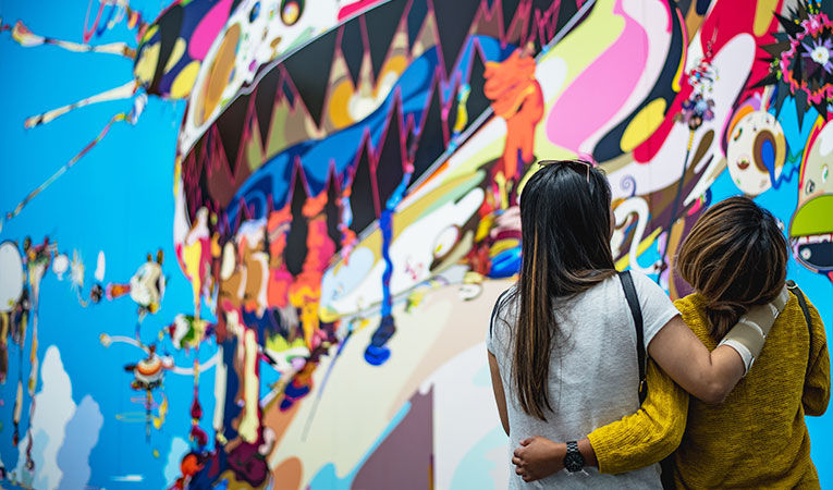 Two girls hugging by a mural