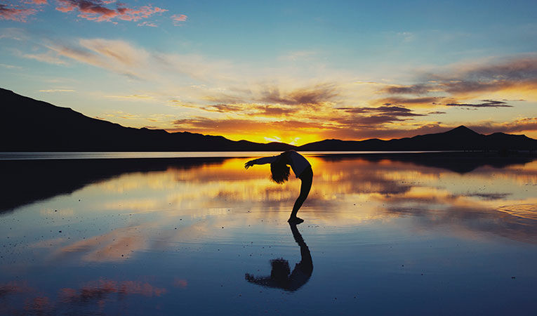 Woman doing a yoga pose on the beach at sunset
