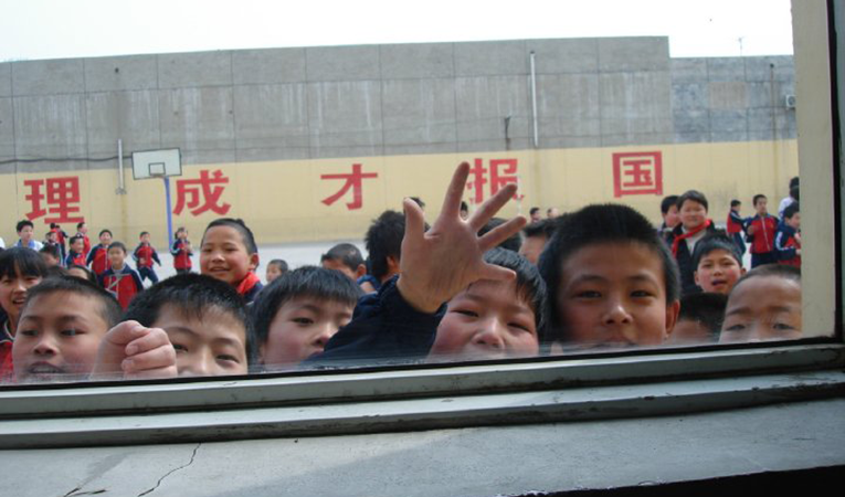 Young Chinese school boys peeking in through a window