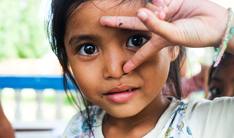 Young brown girl holding up peace sign