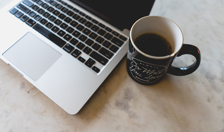 how to get tefl certification online. Mac laptop on table with a cup of coffee.