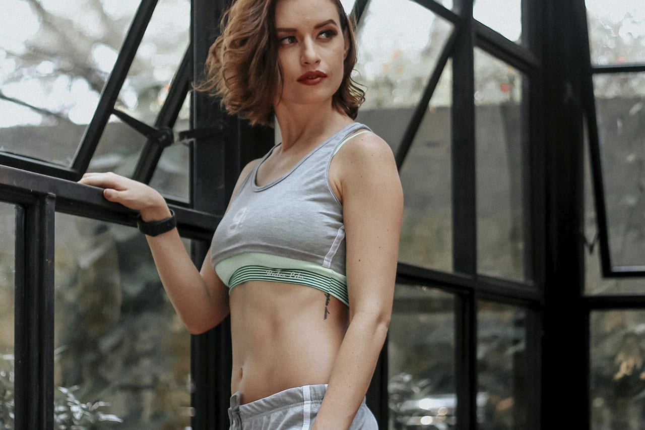 Woman with toned abdomen standing indoors, illustrating results and safety considerations of tummy tuck procedures