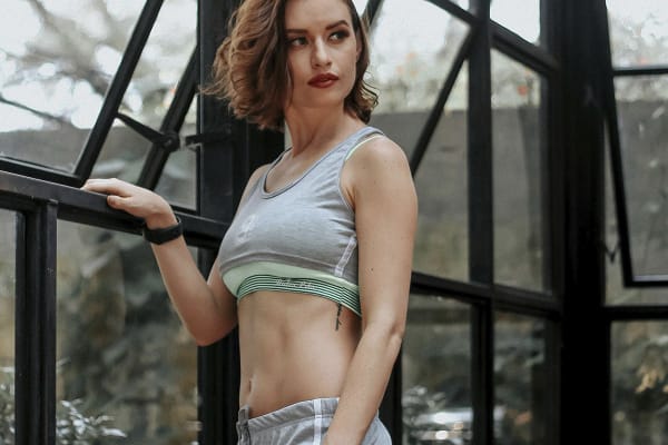 Woman with toned abdomen standing indoors, illustrating results and safety considerations of tummy tuck procedures