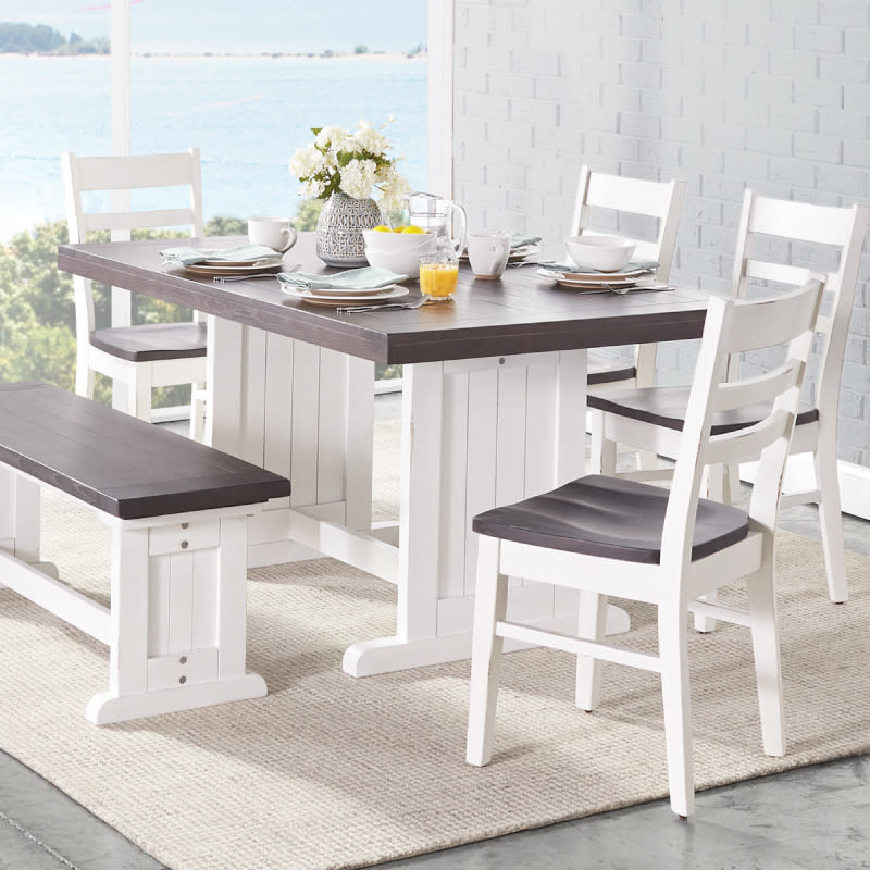 A wooden dining set painted white with natural brown seats including a dining table, four chairs, and a bench.