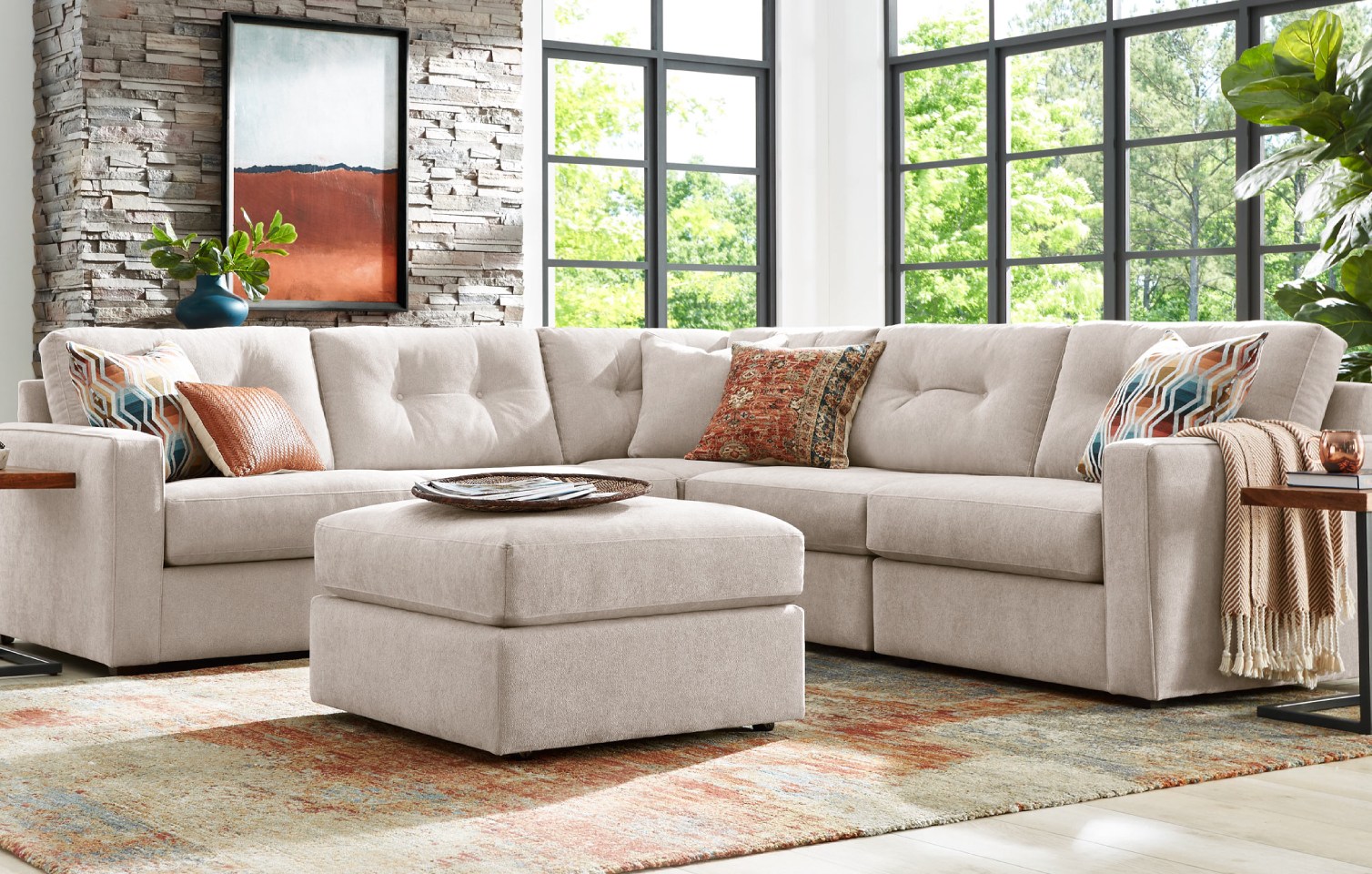 A light gray upholstered L-shaped sectional sofa with a matching square shaped ottoman in a living room.