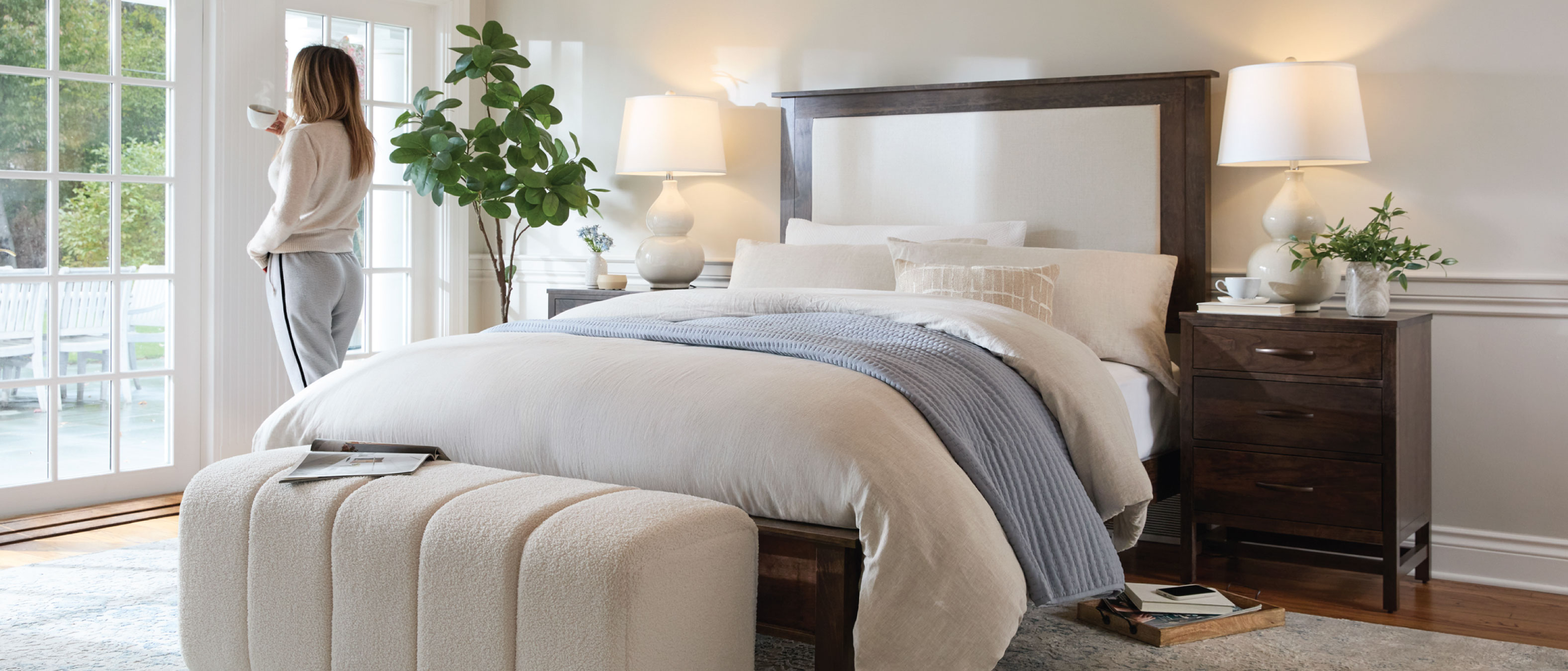 Woman standing in a bedroom next to a Daniel's Amish bed.