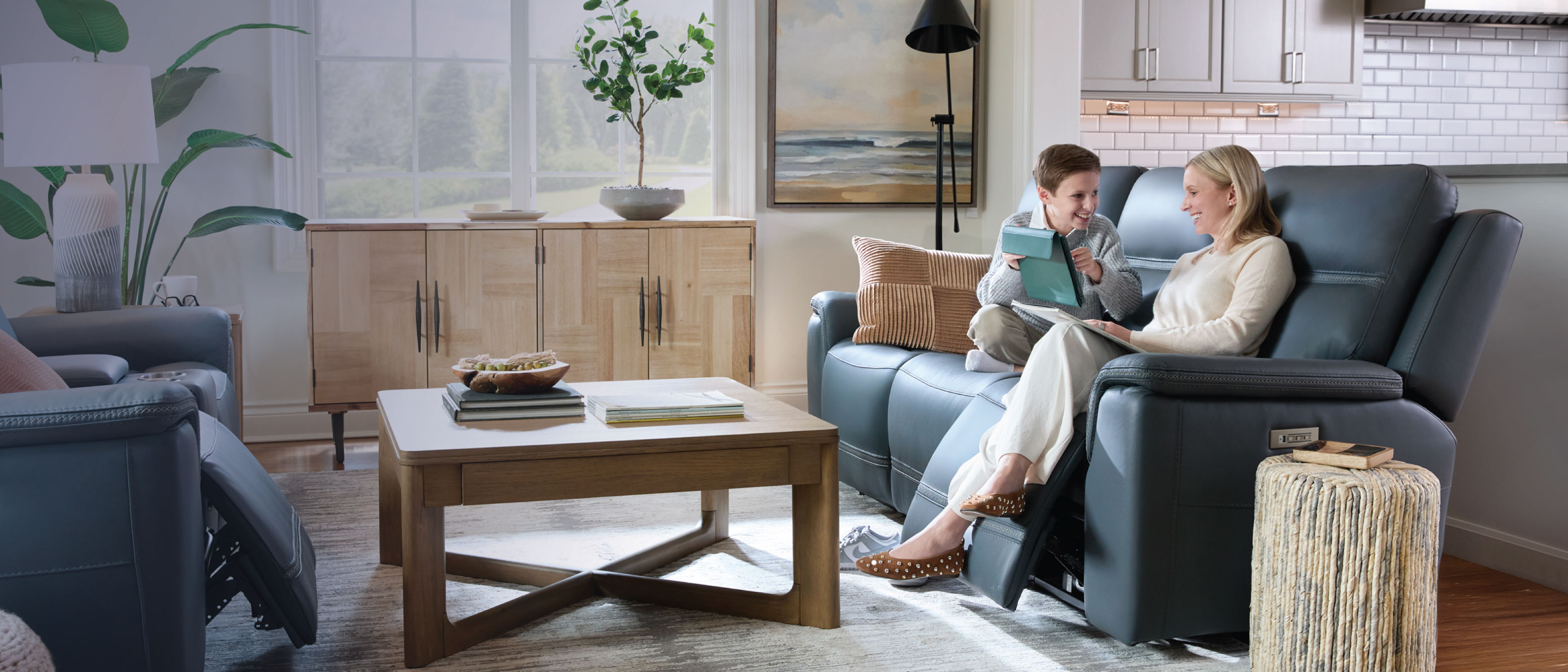 Woman and child sitting on a blue reclining sofa in a living room.