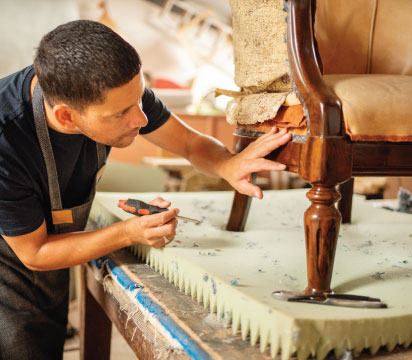 Man assessing damage to a chair in a workshop.