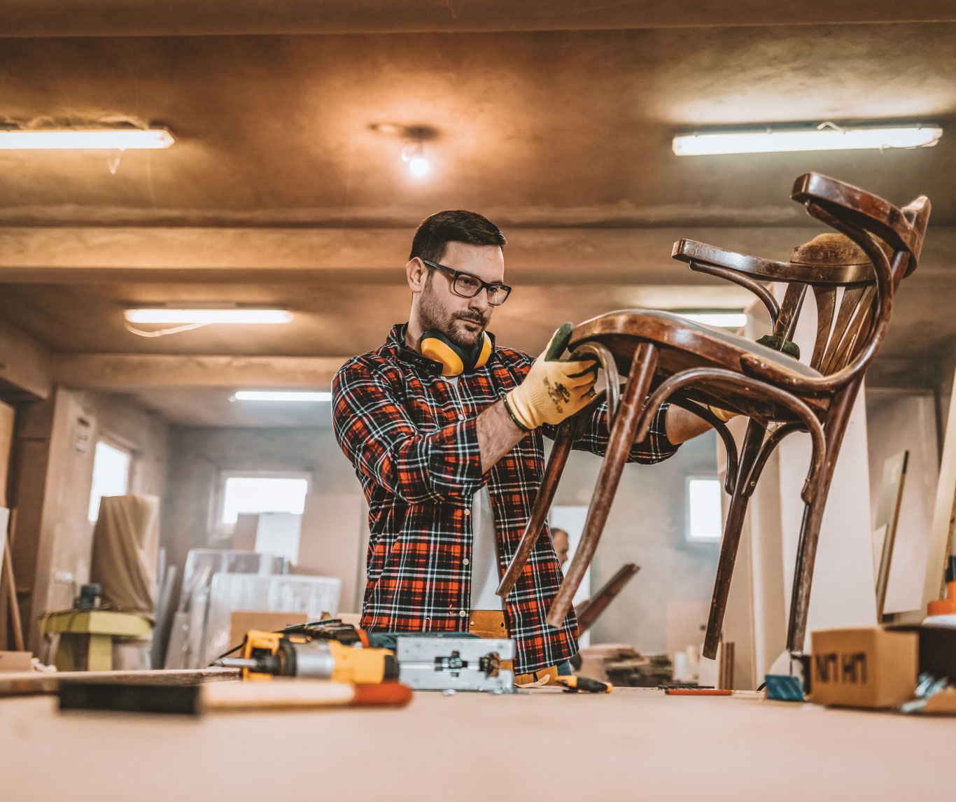 Man in a workshop inspecting a wooden chair.