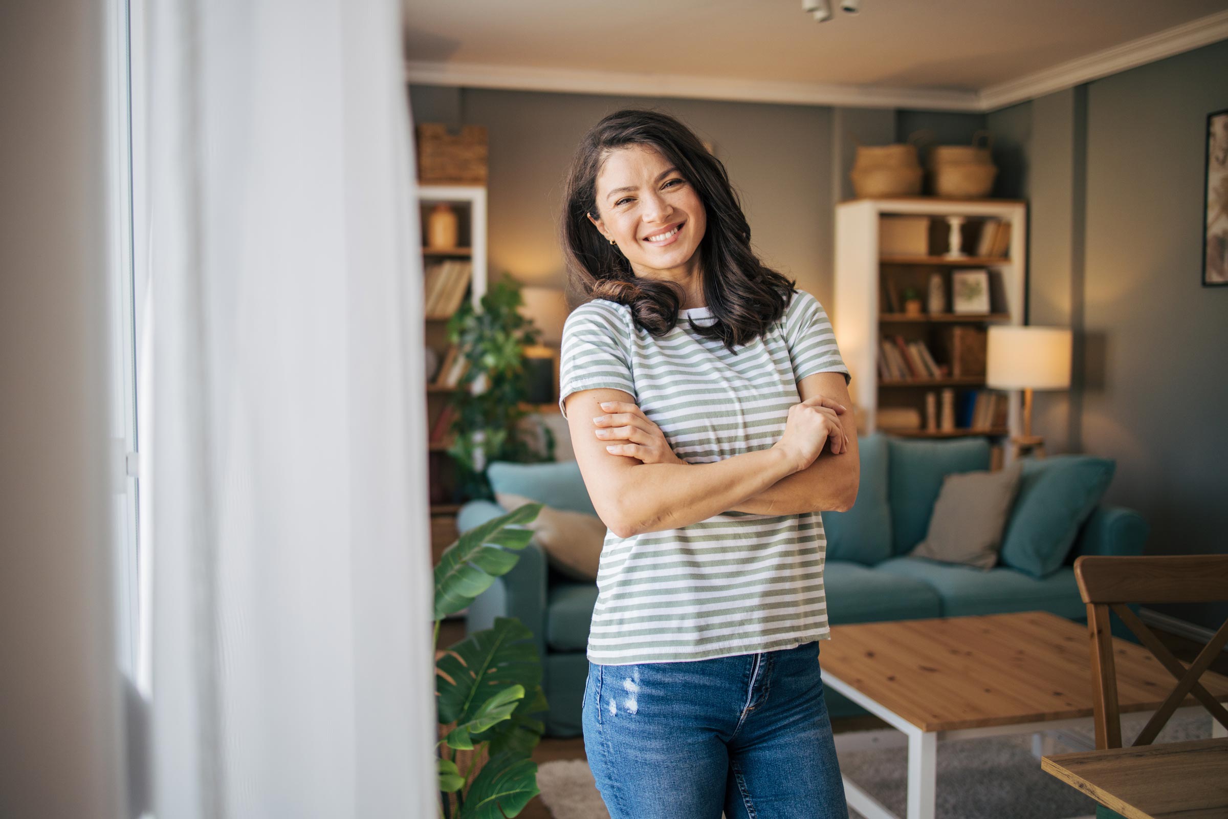 Woman standing in a living room next to furniture.