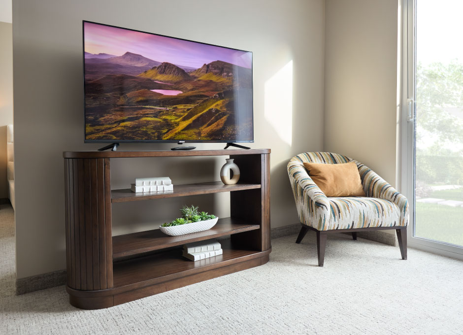 A cozy living room with a media console, accent chair and large TV