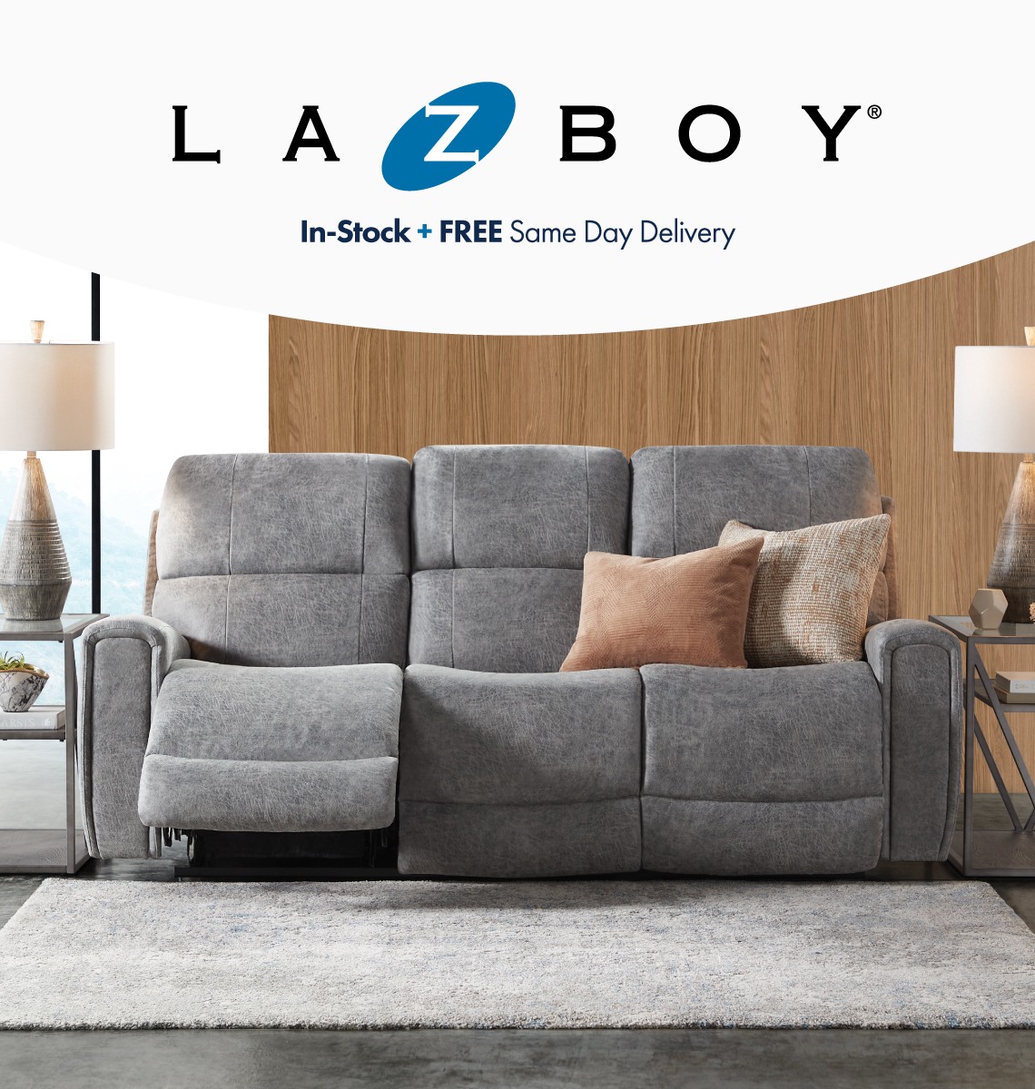 A gray upholstered Lazy Boy sofa with the left seat footrest slightly reclined up.