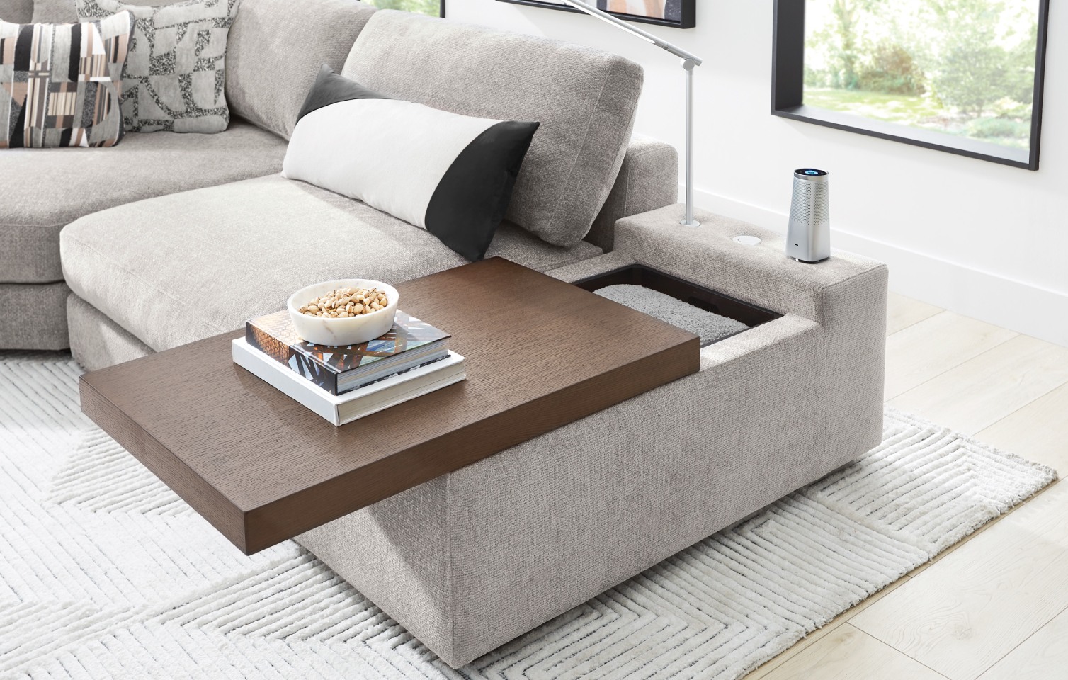 The right side of a light gray modular sectional showing that the console's wooden top can slide to open for storage.
