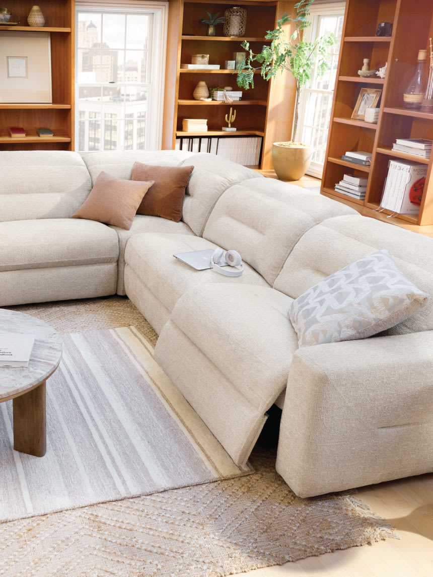 Living room featuring a white reclining sofa, rug, and wooden table.