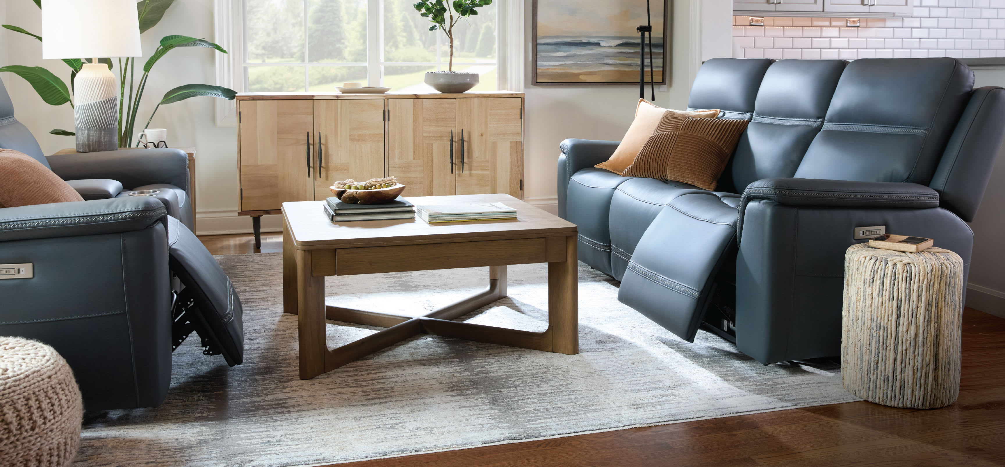 Living room featuring blue reclining sofas, a rug, and wooden table.