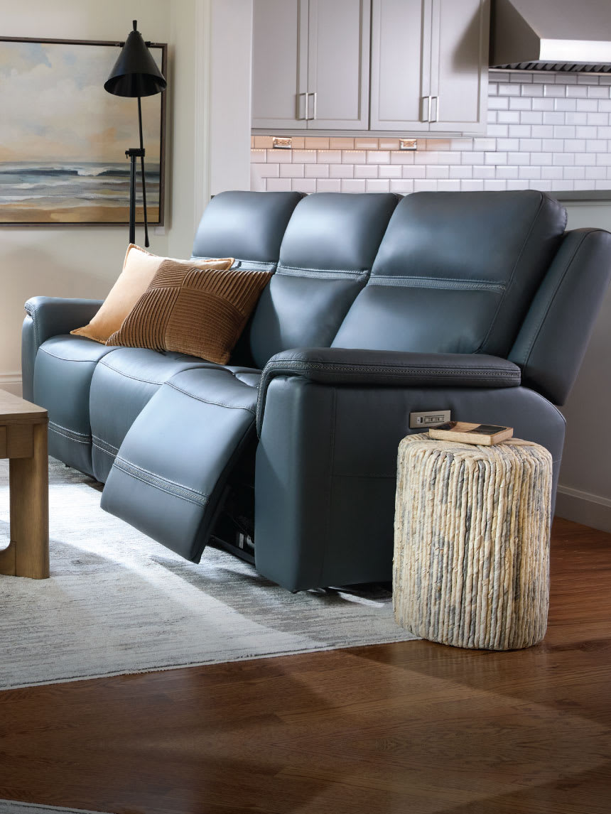 Living room featuring blue reclining sofas, a rug, and wooden table.