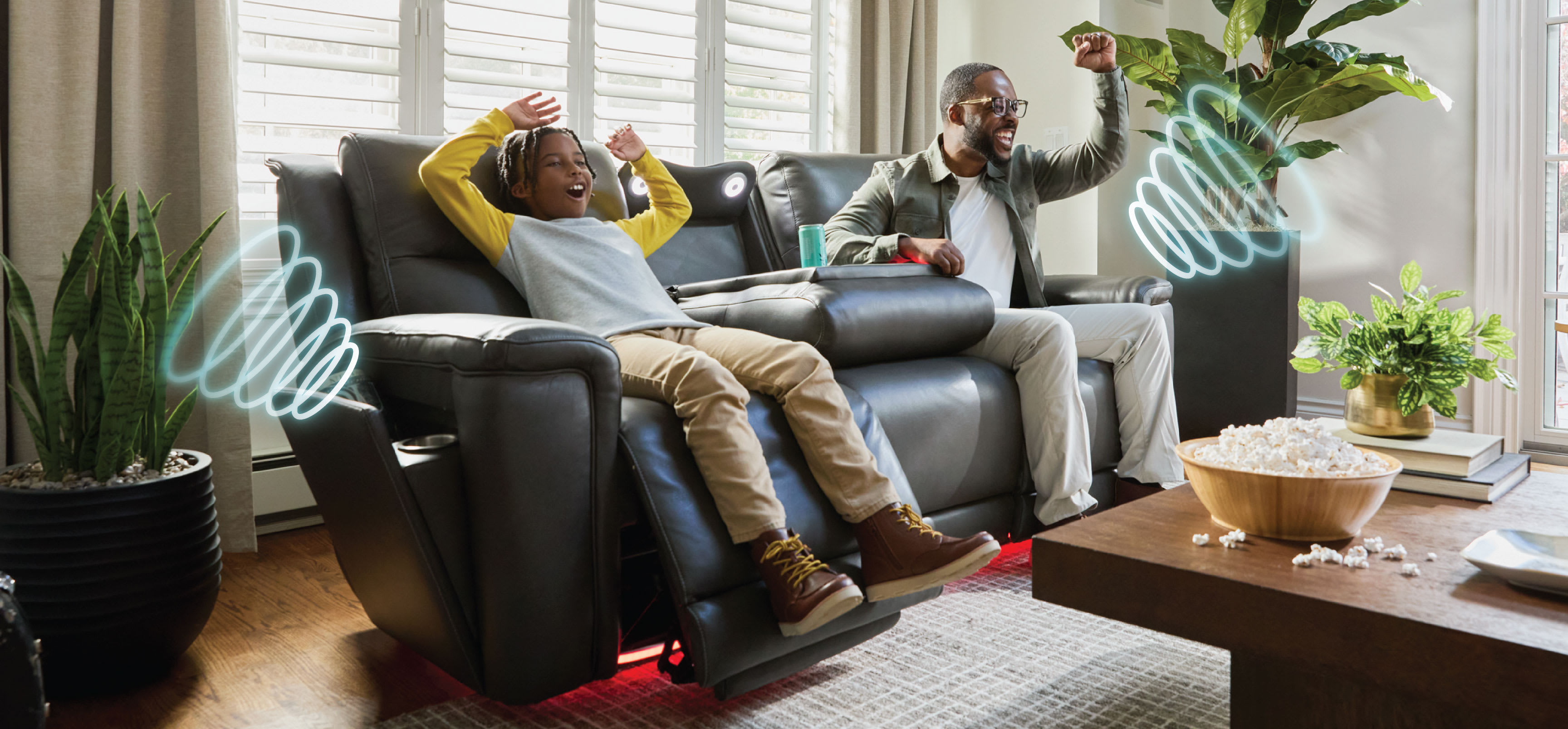 A boy and man are relaxing on a power reclining sofa in a living room.