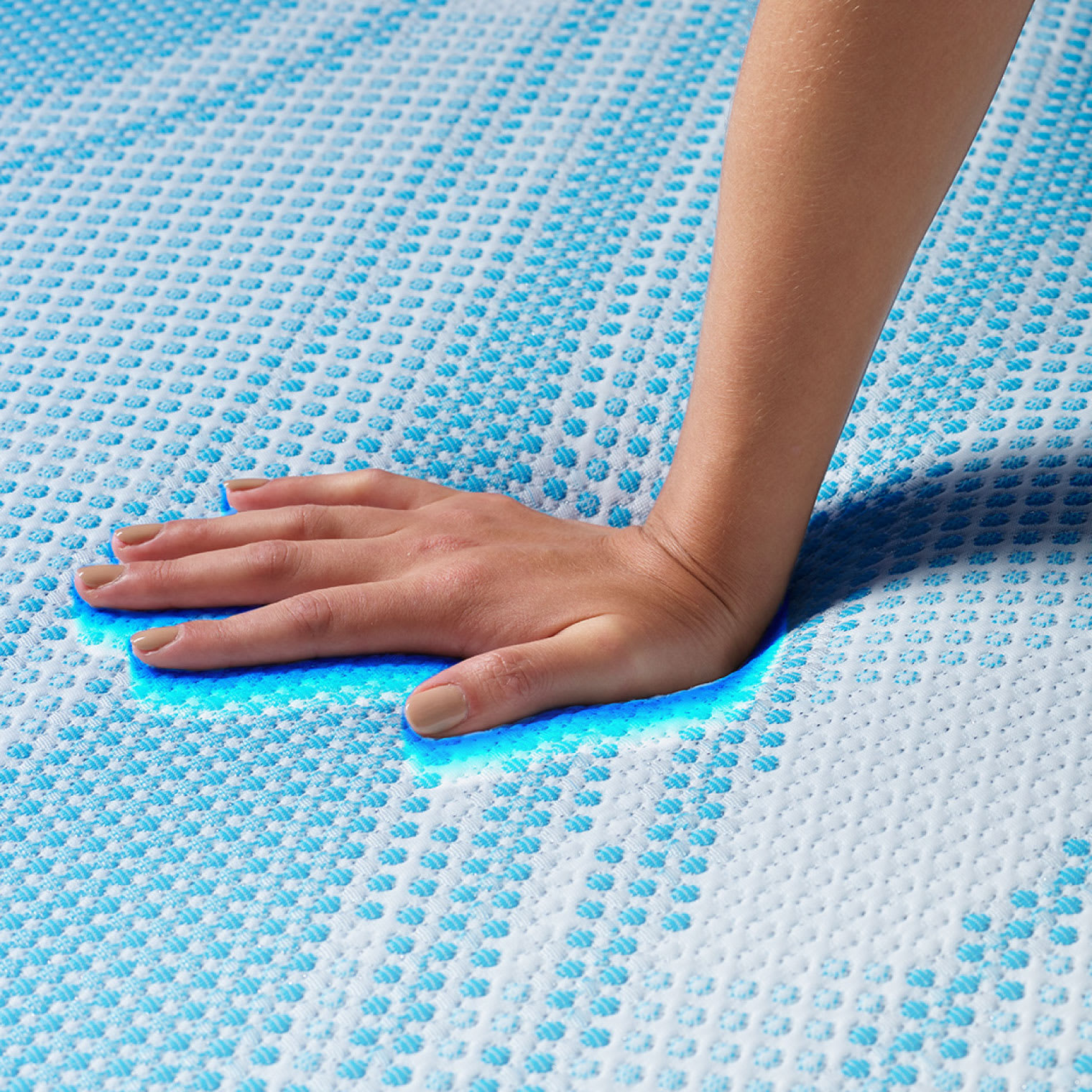 A woman's hand pressing down the top of a memory foam mattress to show how plush it feels.