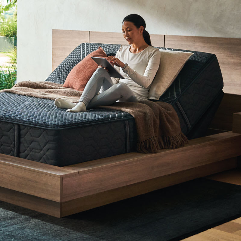 A woman laying on a mattress with an adjustable base.