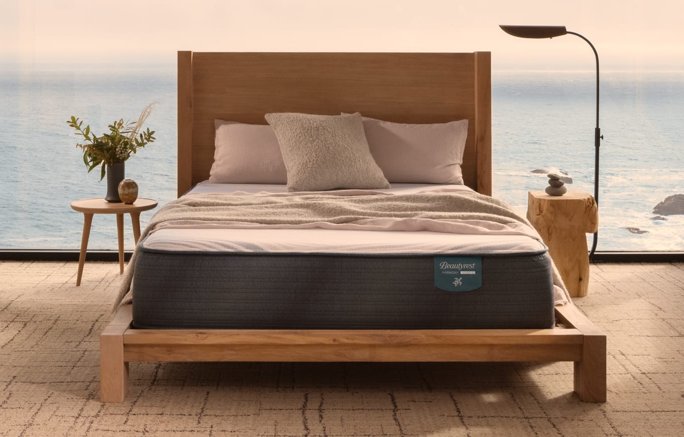 A Beautyrest mattress, queen size, sits atop a wooden bed in a bedroom overlooking the ocean.