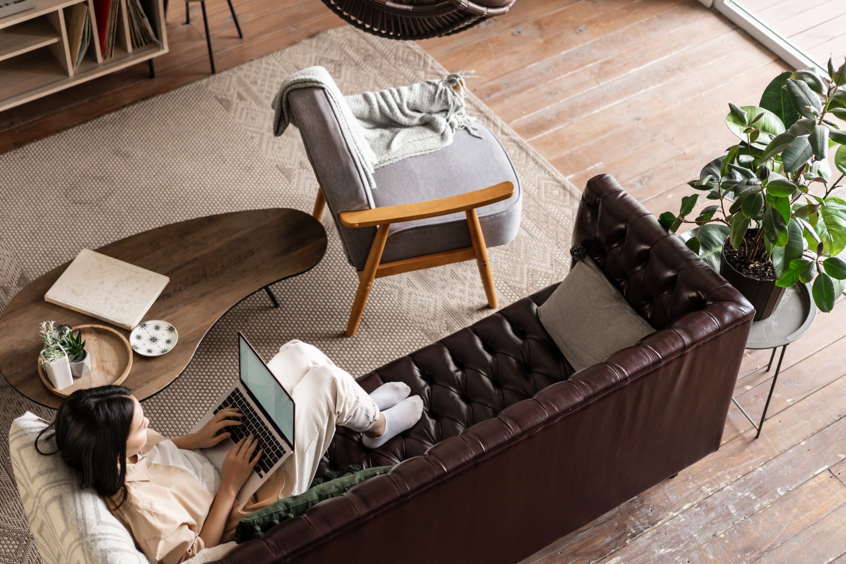 A woman using a laptop while sitting on a leather couch