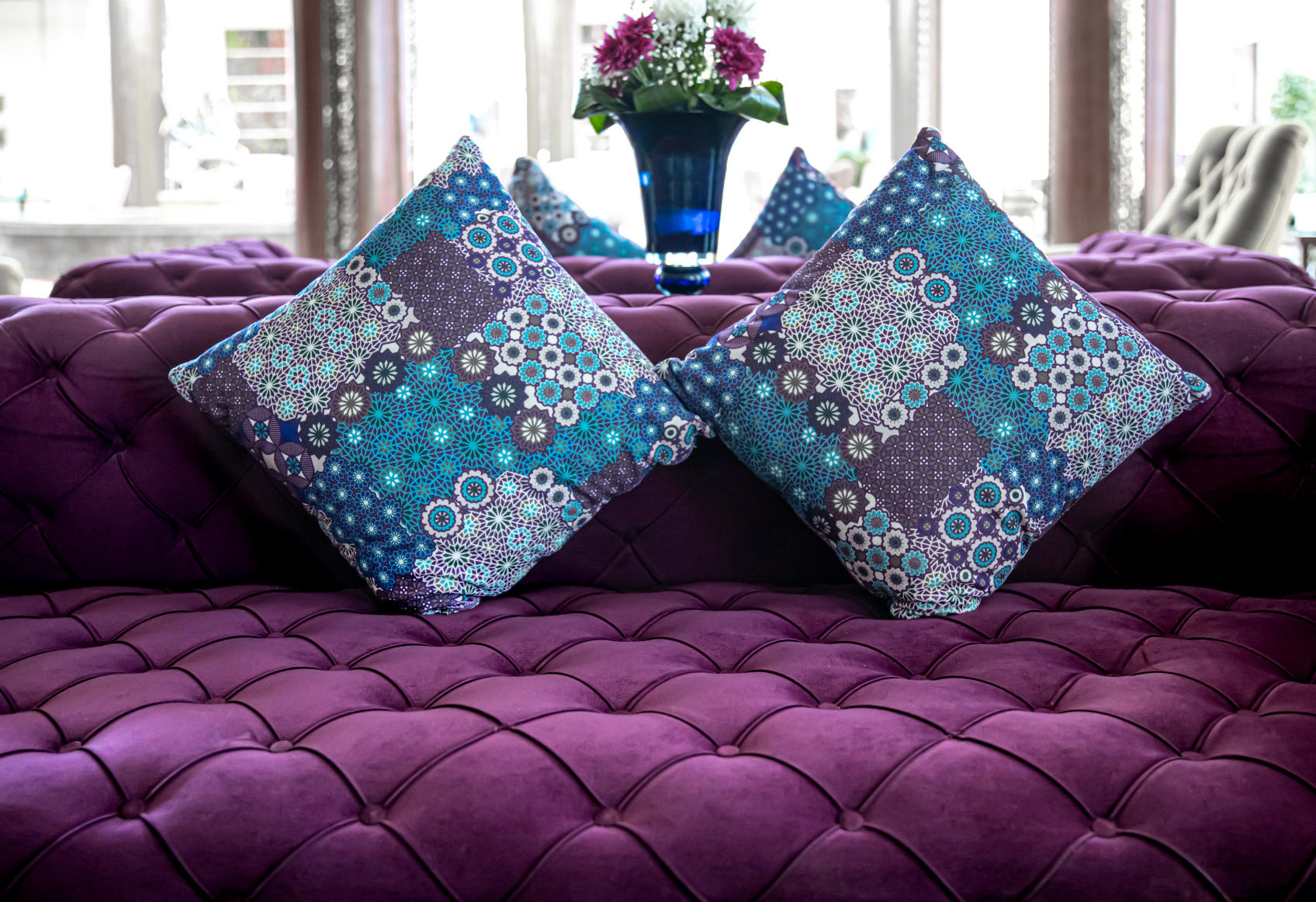 A purple tufted couch with pillows