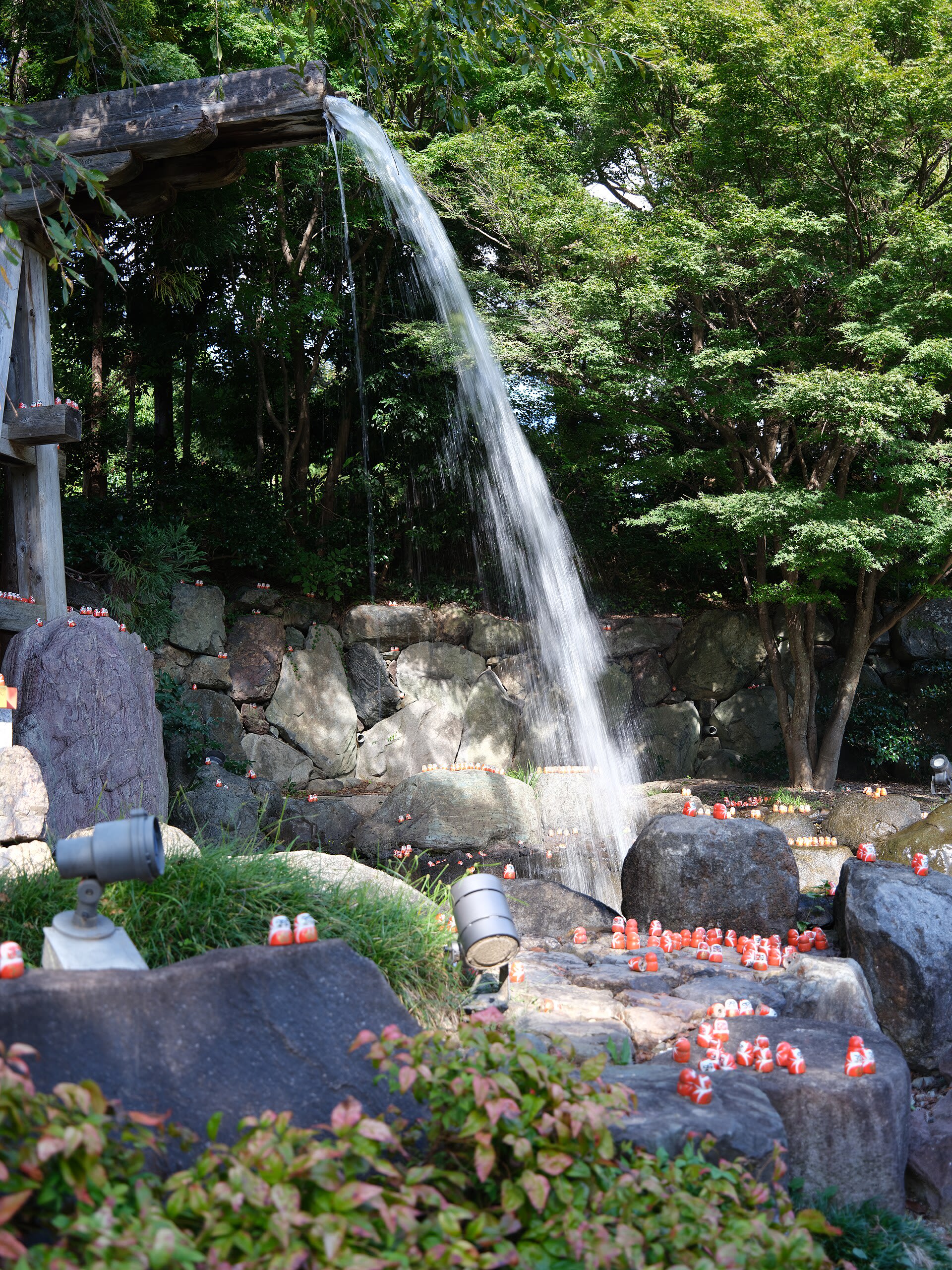 Red Daruma dolls scattered across the rocks in the grounds of Katsuo-ji Temple