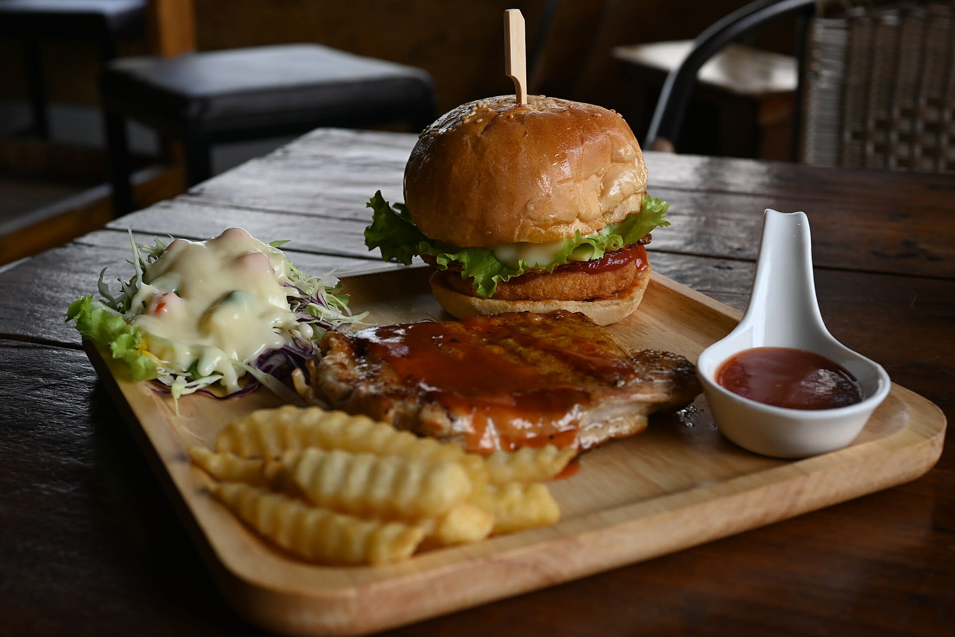 Burger and fries served on a wooden plate at a restaurant