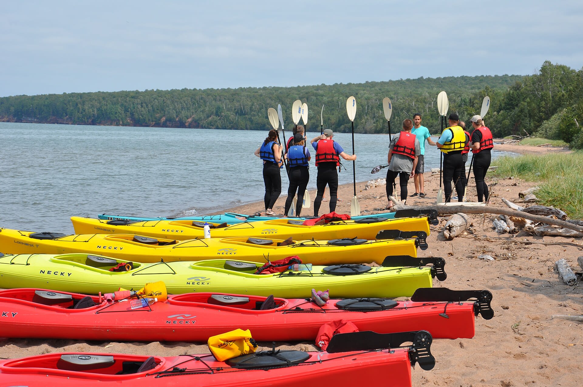 Kayakers gather on the shore before paddling out to the Apostle Islands sea caves