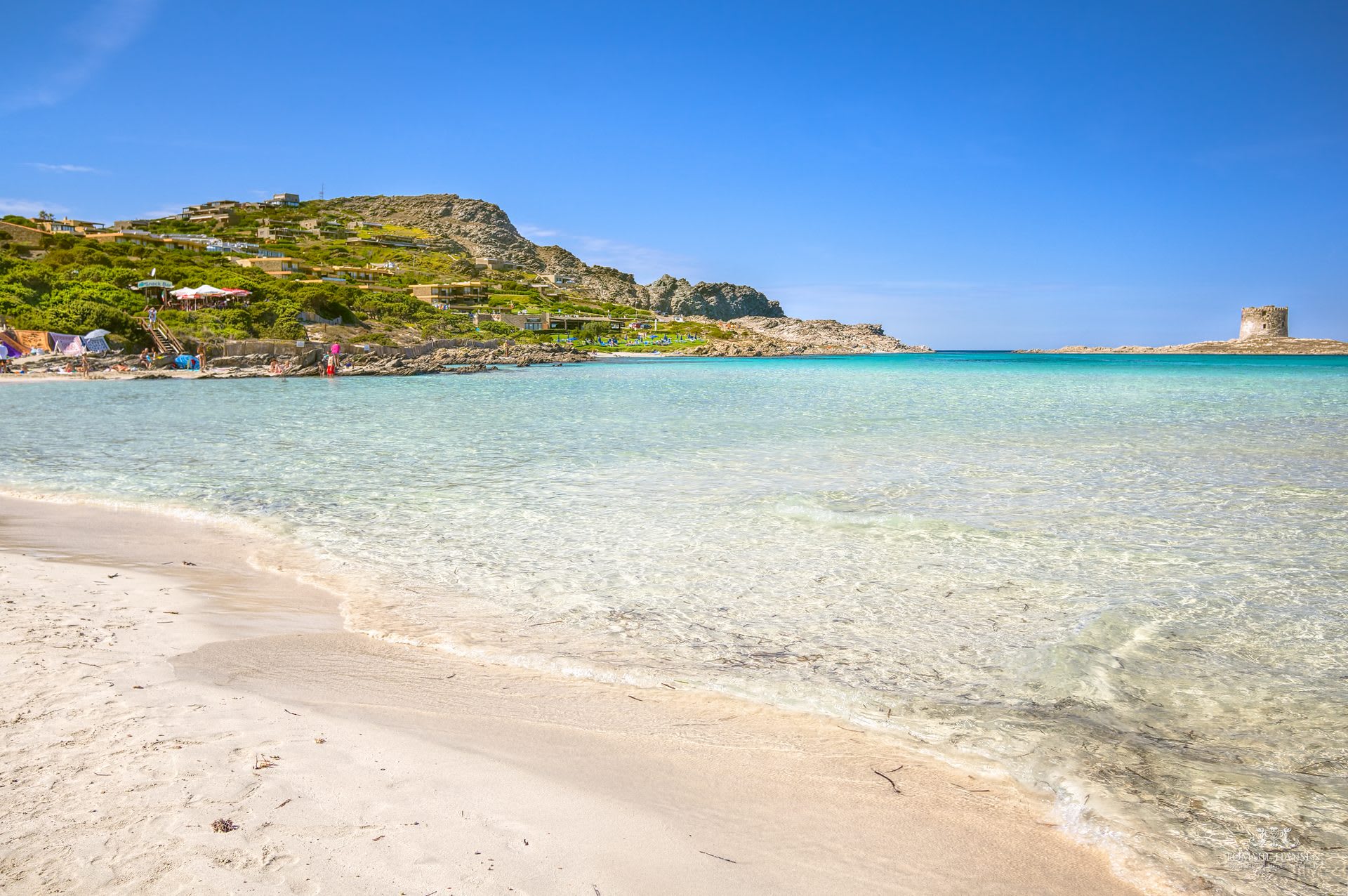 La Pelosa's turquoise shallows near Stintino, with the Torre della Pelosa watchtower visible offshore
