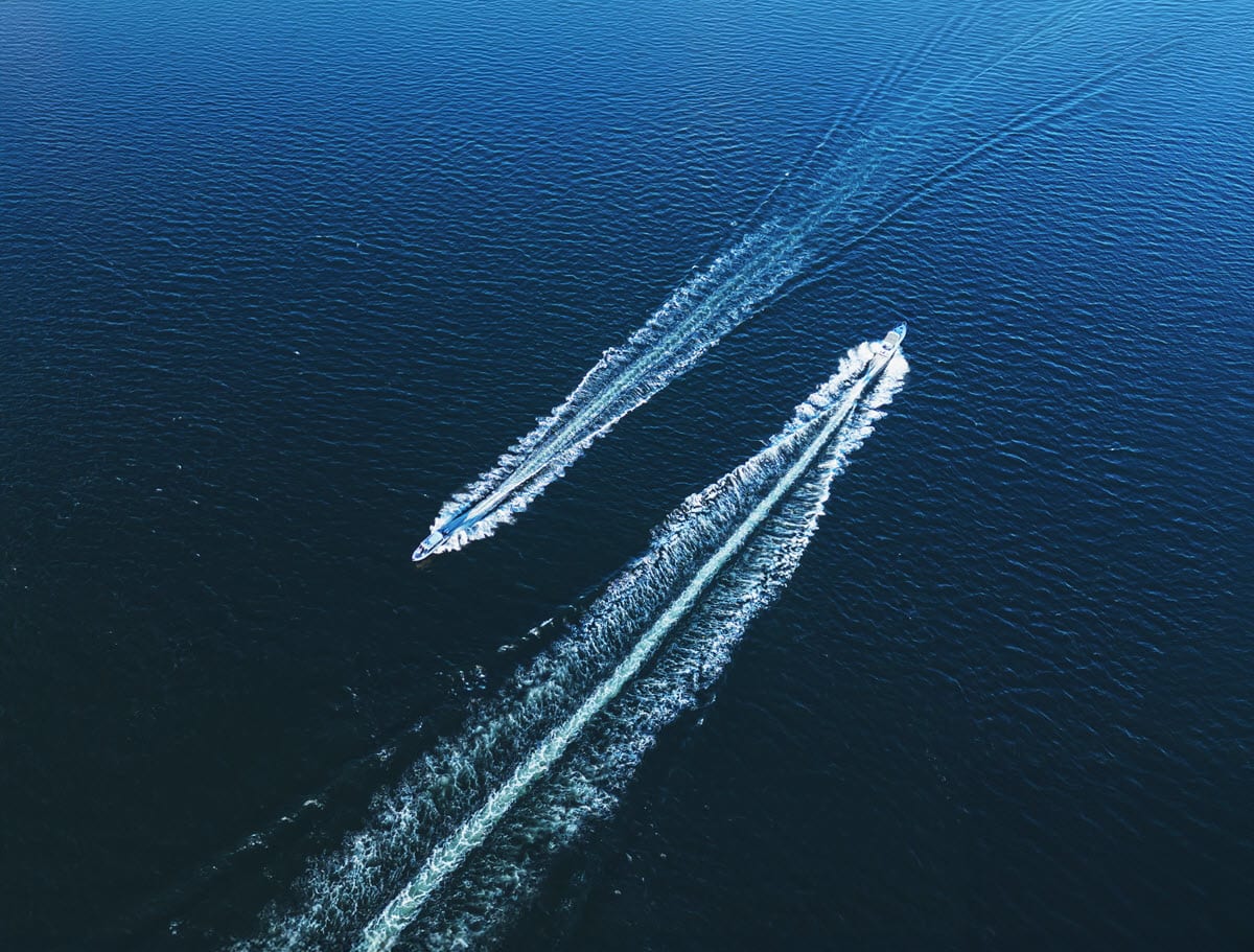 Two motorboats going past each other in opposite directions on a dark blue sea