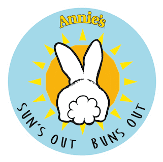 A circular aqua colored sticker showing the backside of a rabbit in front of the sun. It says "Annie's - Sun's out Buns out"
