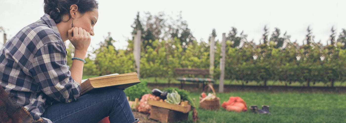 a girl reading a book in a garden